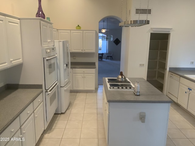 kitchen with white cabinetry, a center island, light tile patterned floors, and white appliances