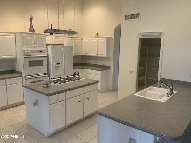 kitchen featuring white cabinetry, sink, light tile patterned floors, and white appliances