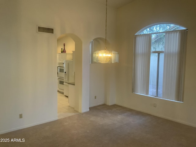 carpeted empty room with a chandelier