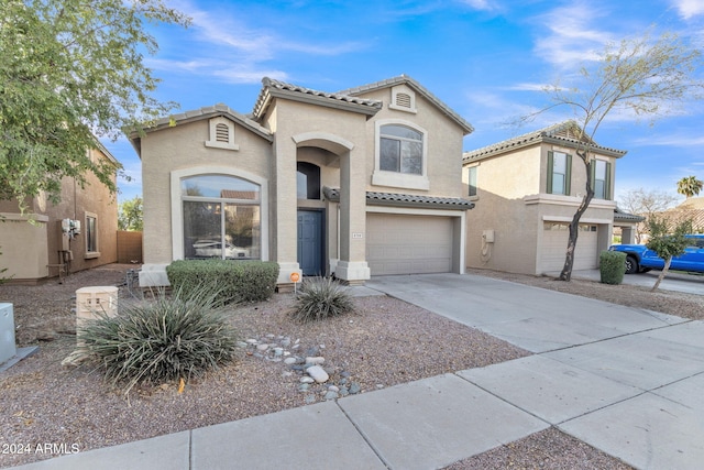 mediterranean / spanish home with driveway, an attached garage, a tile roof, and stucco siding