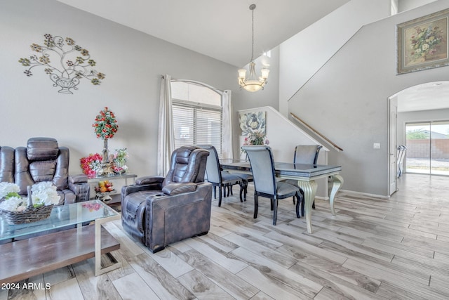 interior space featuring light wood finished floors, baseboards, arched walkways, high vaulted ceiling, and a chandelier