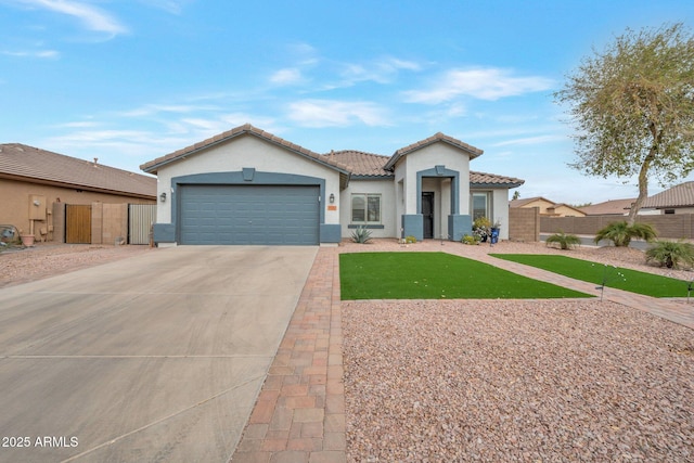 mediterranean / spanish-style house with fence, a tiled roof, stucco siding, a garage, and driveway