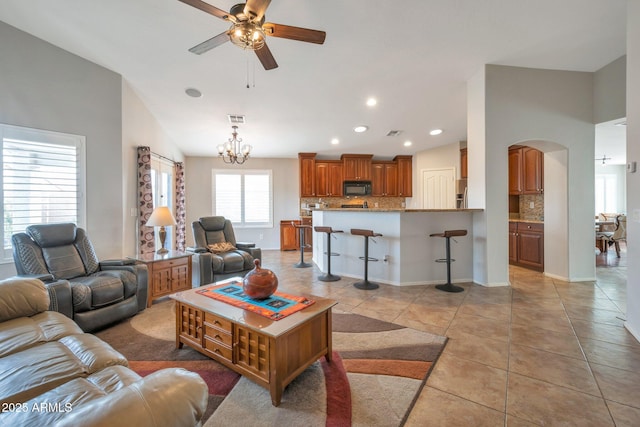 living area featuring visible vents, ceiling fan with notable chandelier, recessed lighting, arched walkways, and light tile patterned flooring