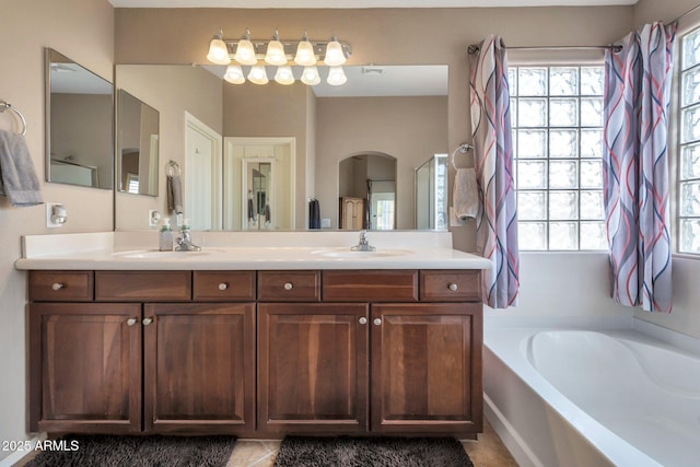 full bathroom featuring a sink, a garden tub, and double vanity