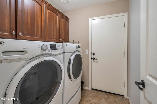 laundry area featuring washer and dryer, baseboards, cabinet space, and light tile patterned floors