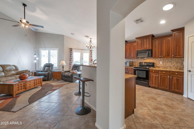 kitchen featuring visible vents, black appliances, open floor plan, a kitchen breakfast bar, and tasteful backsplash