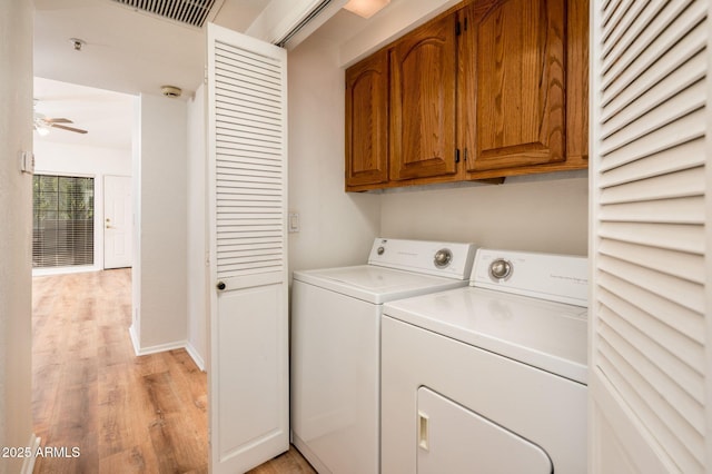 clothes washing area featuring washer and dryer, light hardwood / wood-style flooring, cabinets, and ceiling fan