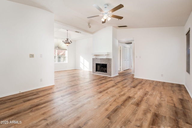 unfurnished living room with lofted ceiling, a fireplace, ceiling fan with notable chandelier, and wood-type flooring