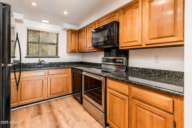 kitchen with light hardwood / wood-style flooring, sink, dark stone countertops, and black appliances