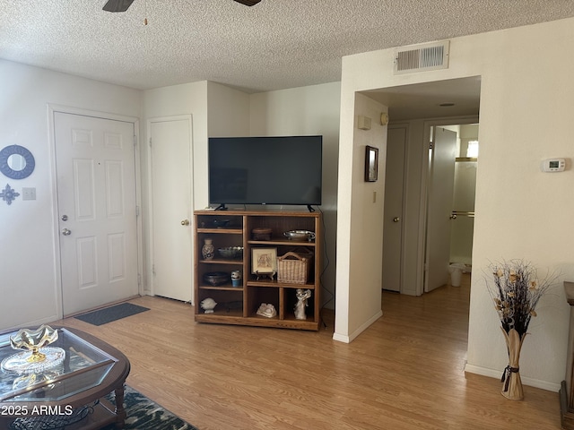 living room with ceiling fan, light hardwood / wood-style floors, and a textured ceiling