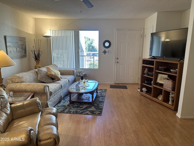 living room with ceiling fan, hardwood / wood-style flooring, and a textured ceiling