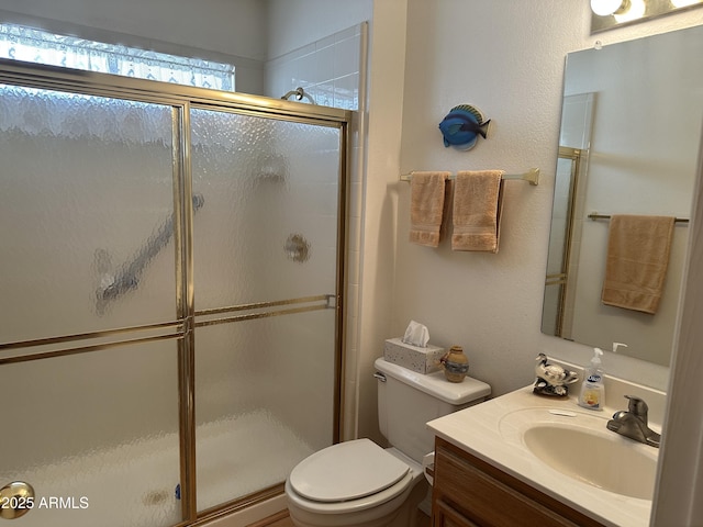 bathroom with vanity, a shower with door, and toilet