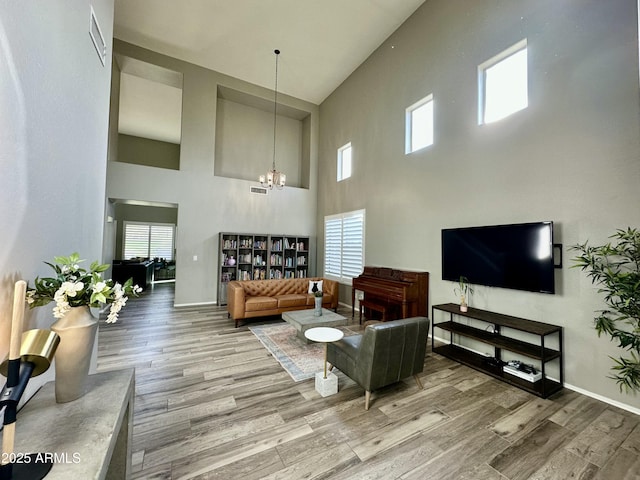 living room with wood-type flooring, a chandelier, and a high ceiling