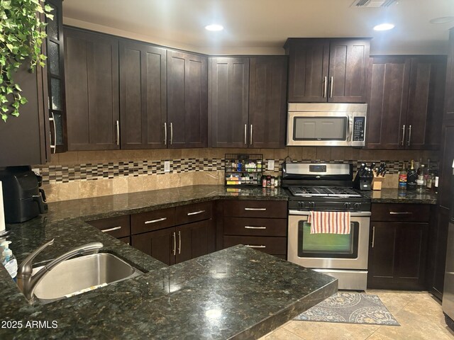5350 E Deer Valley Dr Unit 3267, Phoenix, AZ 85054 - kitchen with stainless steel appliances, dark brown cabinetry, backsplash, a sink, and dark stone counters
