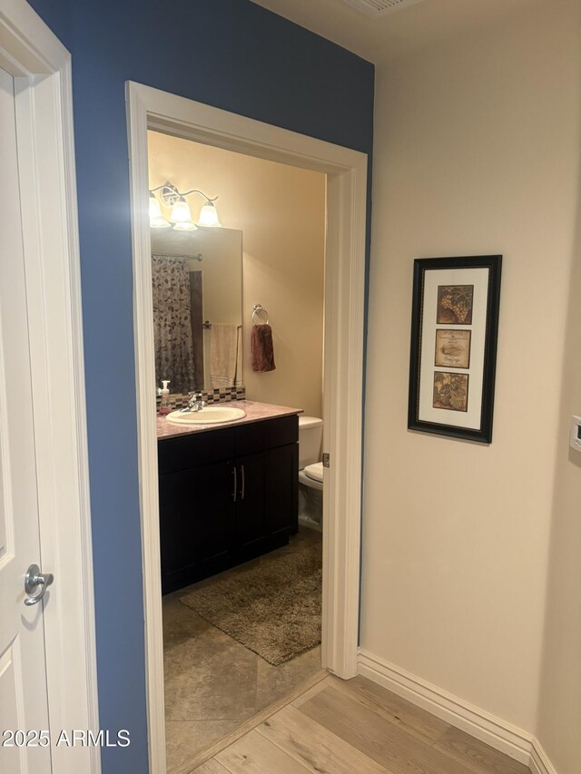 5350 E Deer Valley Dr Unit 3267, Phoenix, AZ 85054 - bathroom featuring wood finished floors, toilet, vanity, and baseboards