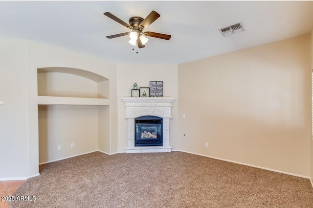 unfurnished living room featuring built in features, ceiling fan, and carpet