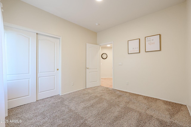 unfurnished bedroom featuring light carpet and a closet