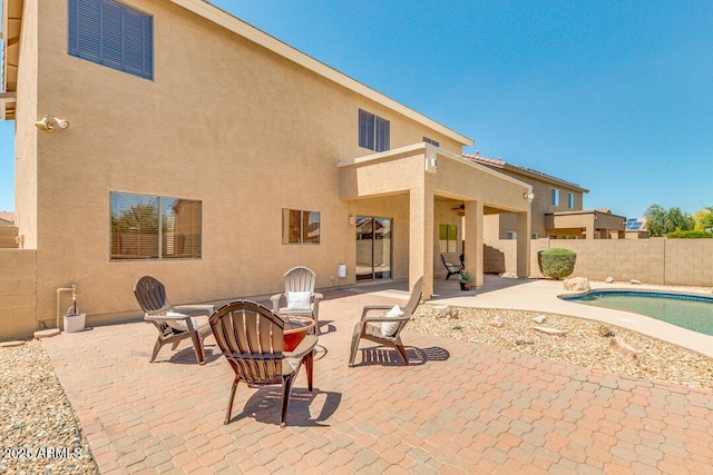 back of property featuring a fenced in pool, a patio, and an outdoor fire pit