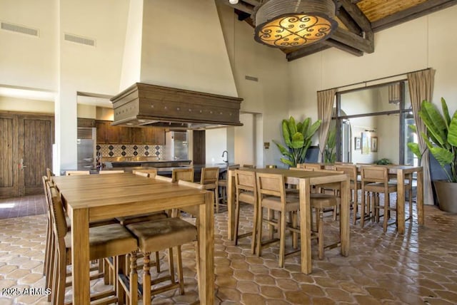 dining room featuring beamed ceiling and a towering ceiling