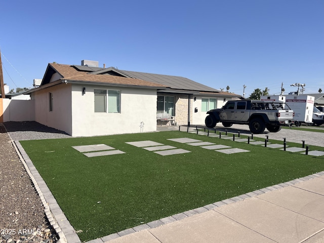 exterior space with solar panels and a front yard