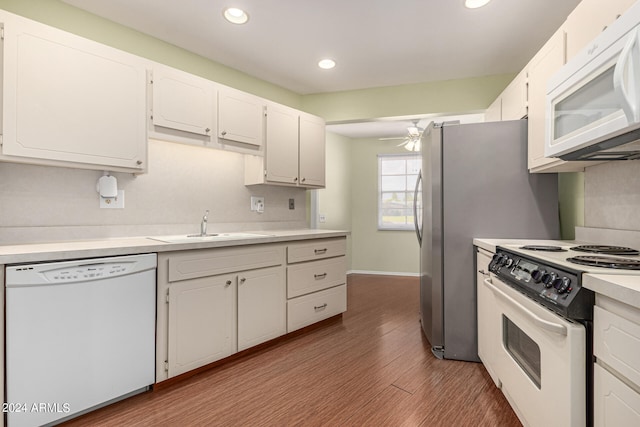 kitchen with white appliances, ceiling fan, sink, hardwood / wood-style floors, and white cabinetry