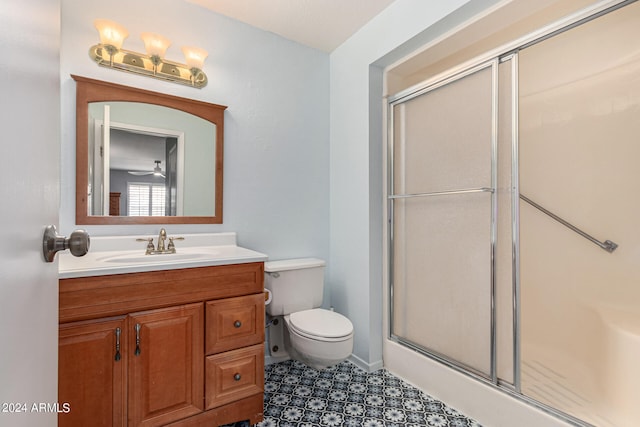 bathroom featuring vanity, toilet, an enclosed shower, and ceiling fan