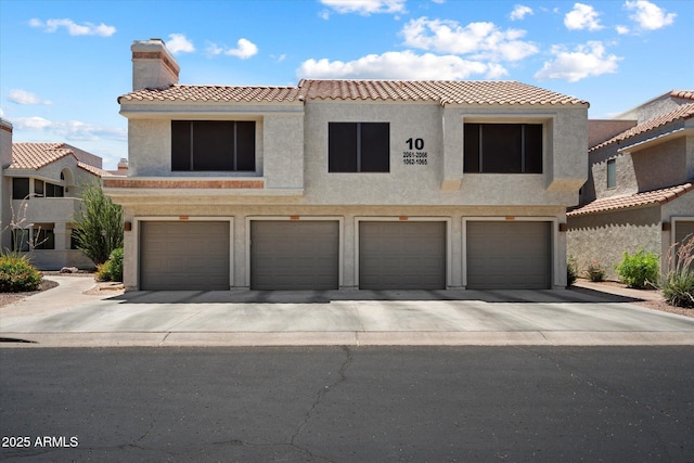 10115 E Mountain View Rd Unit 2061, Scottsdale, AZ 85258 - view of front of property featuring a chimney, a garage, a tiled roof, and stucco siding