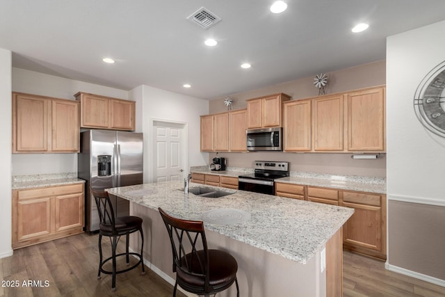 kitchen with stainless steel appliances, hardwood / wood-style floors, sink, and a center island with sink