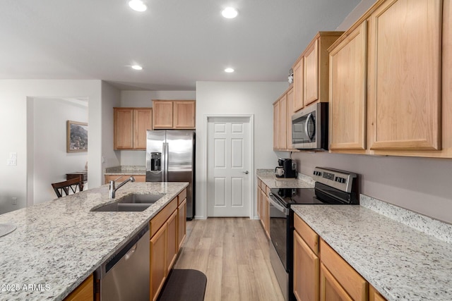 kitchen featuring light stone counters, sink, stainless steel appliances, and light hardwood / wood-style floors