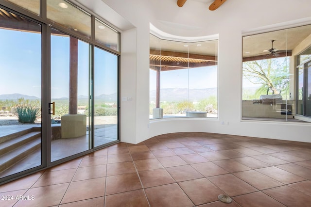 unfurnished sunroom with a mountain view and ceiling fan