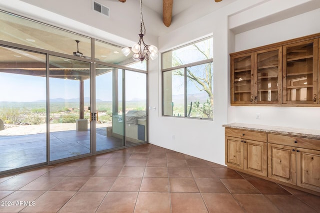 doorway with a mountain view, tile patterned floors, a notable chandelier, beam ceiling, and a wall of windows