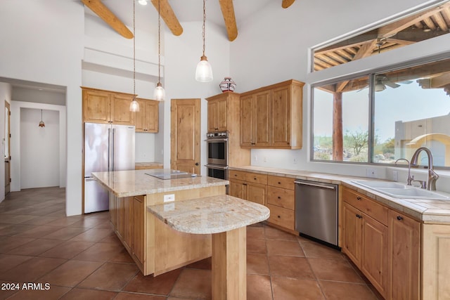 kitchen with stainless steel appliances, sink, beam ceiling, high vaulted ceiling, and an island with sink