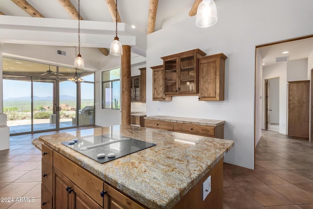 kitchen featuring a mountain view, black electric stovetop, hanging light fixtures, ceiling fan, and a kitchen island