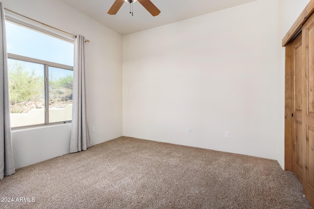 carpeted spare room featuring ceiling fan