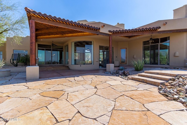 rear view of house with ceiling fan and a patio