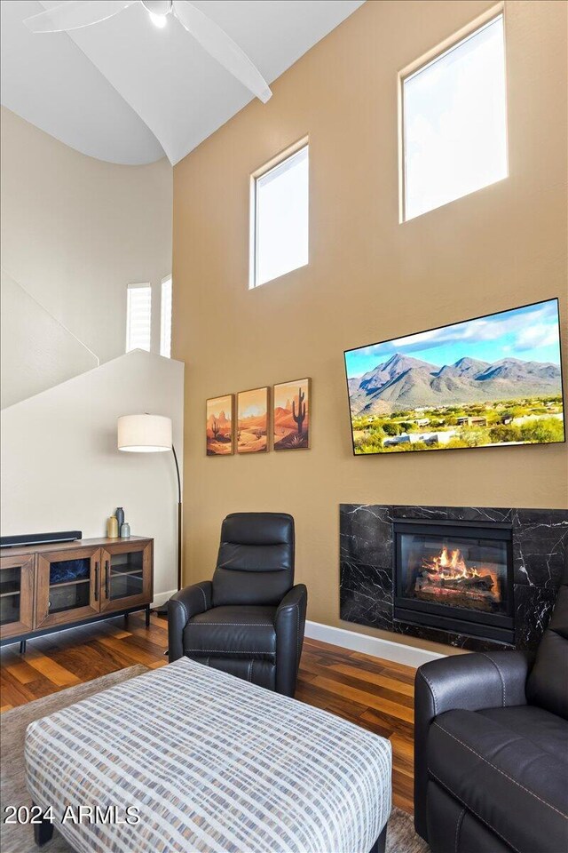 19475 N Grayhawk Dr Unit 1115, Scottsdale, AZ 85255 - living room featuring a high ceiling, wood finished floors, a premium fireplace, ceiling fan, and baseboards