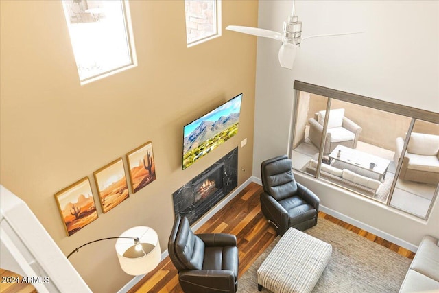 19475 N Grayhawk Dr Unit 1115, Scottsdale, AZ 85255 - living area featuring a high end fireplace, wood finished floors, a towering ceiling, a ceiling fan, and baseboards