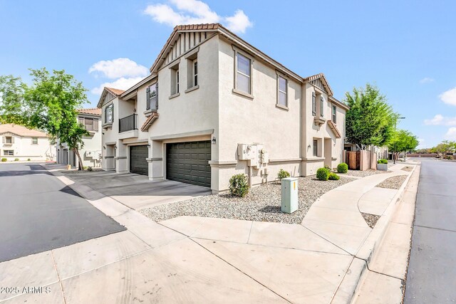 view of home's exterior with a tiled roof, stucco siding, an attached garage, driveway, and a residential view