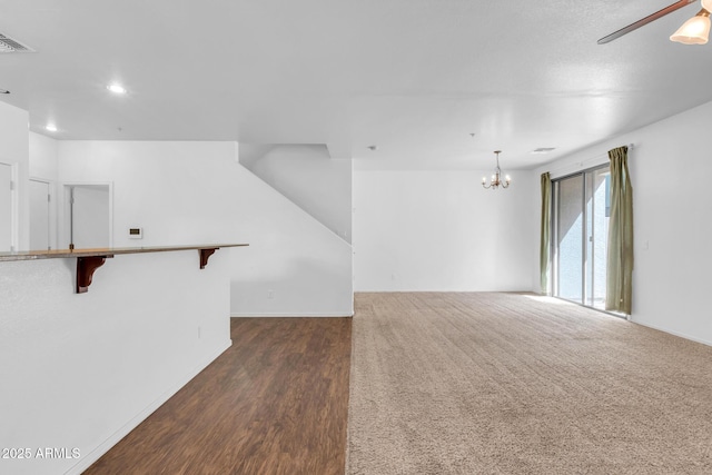 unfurnished room featuring ceiling fan with notable chandelier, visible vents, recessed lighting, dark wood-style flooring, and baseboards