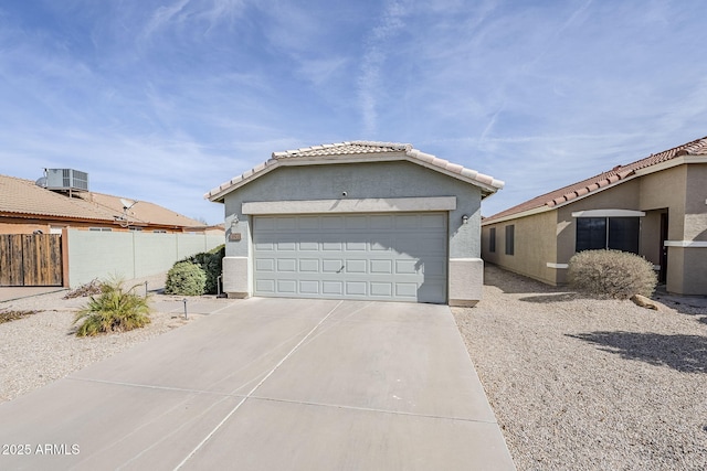 view of front of property with central AC unit, a garage, fence, concrete driveway, and stucco siding