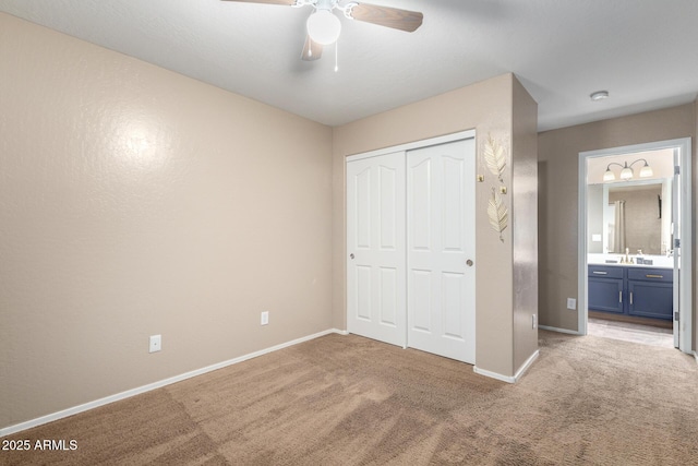 unfurnished bedroom featuring sink, a closet, ceiling fan, and carpet