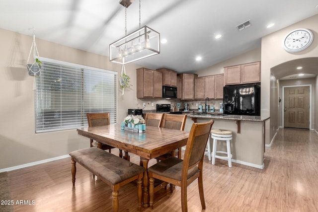 dining room with lofted ceiling, sink, and light hardwood / wood-style floors