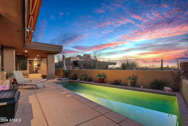 pool at dusk featuring a patio area