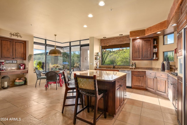 kitchen featuring a center island, light stone counters, a kitchen bar, light tile floors, and stainless steel dishwasher