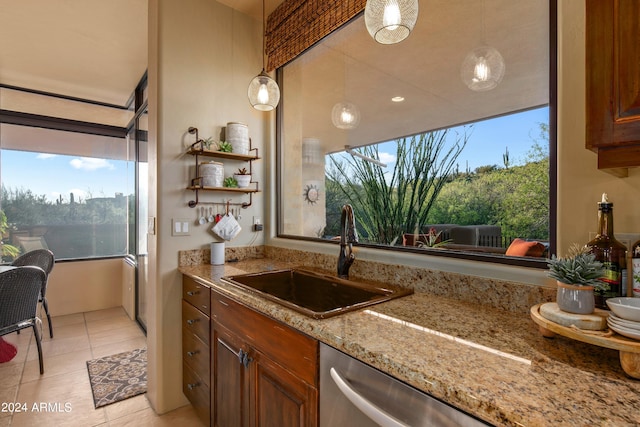 kitchen featuring light stone countertops, light tile flooring, dishwasher, sink, and pendant lighting