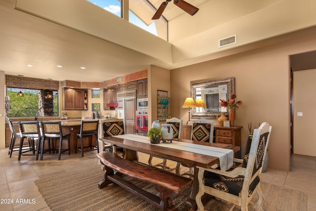 dining space featuring ceiling fan, light tile floors, and a towering ceiling