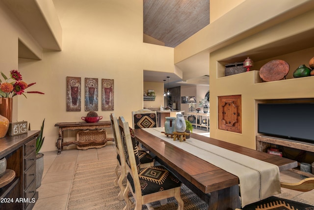 dining room with wooden ceiling, a towering ceiling, and light tile floors