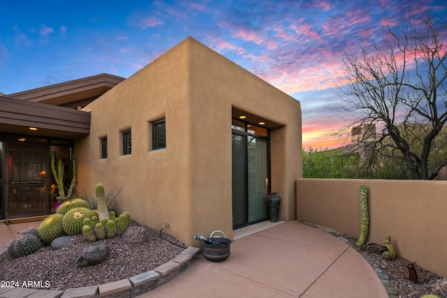 property exterior at dusk with a patio area