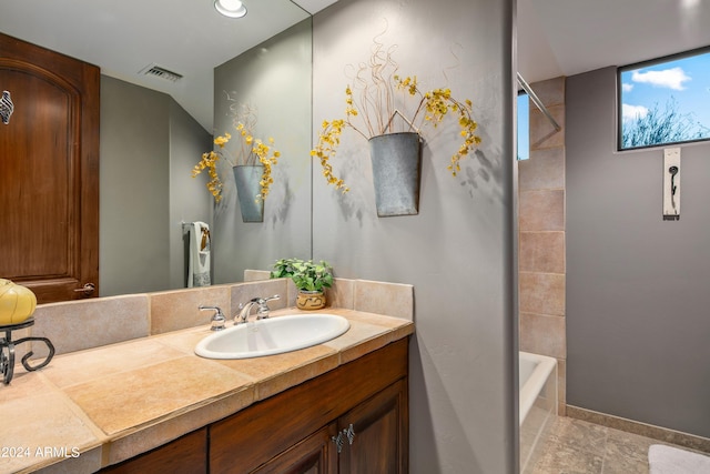 bathroom with tiled shower / bath, vanity, and tile floors