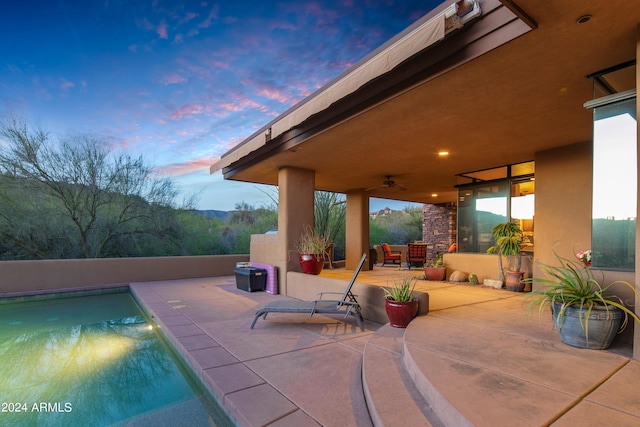 patio terrace at dusk featuring a fenced in pool